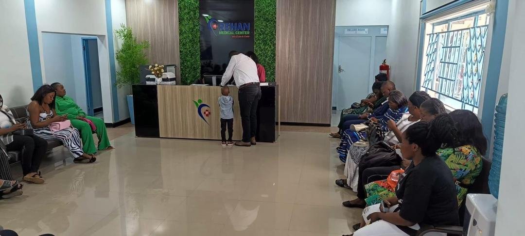a white kitten with brown and black spots sitting with its paws slightly outstretched. 